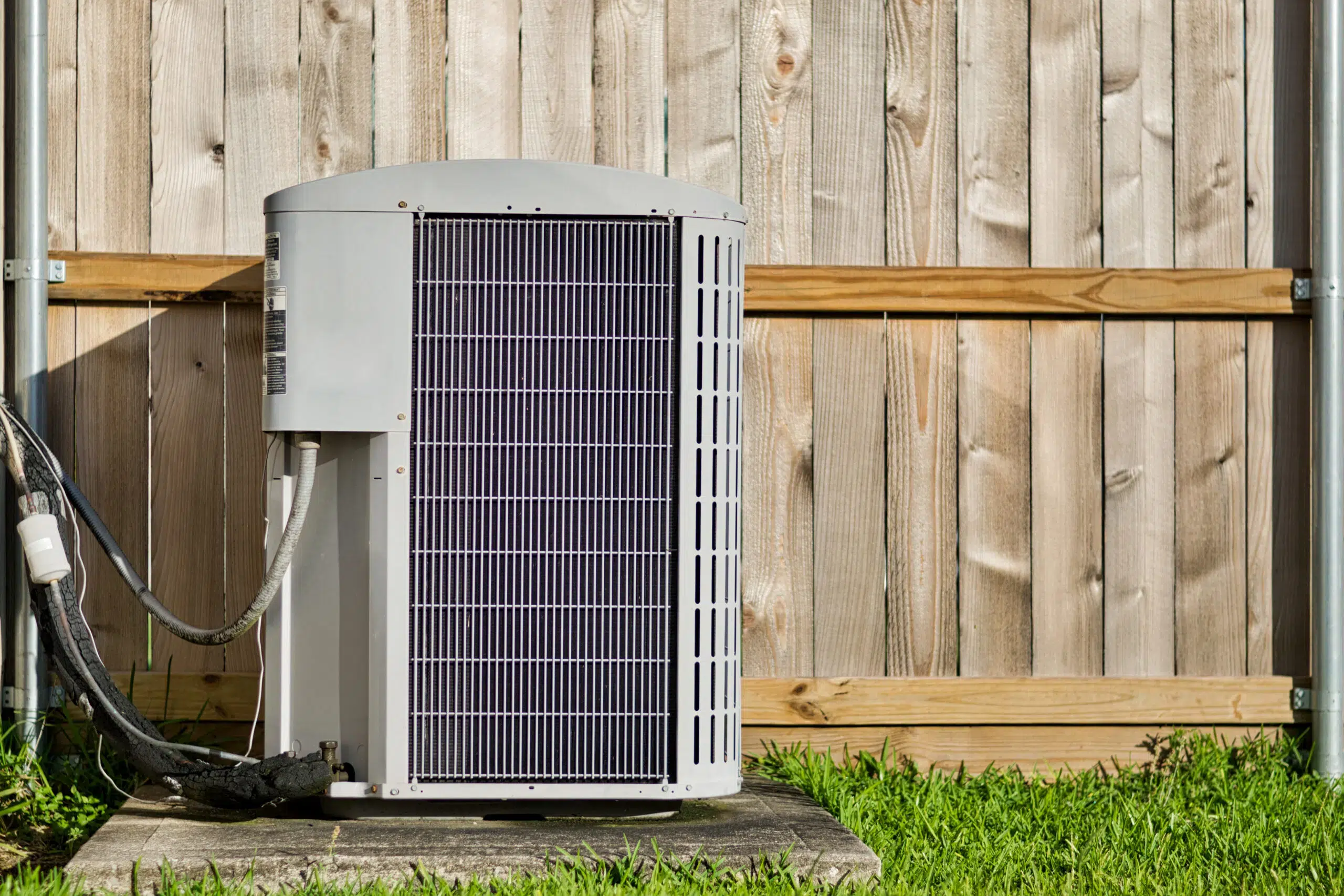 AC unit outside in front of a wooden fence