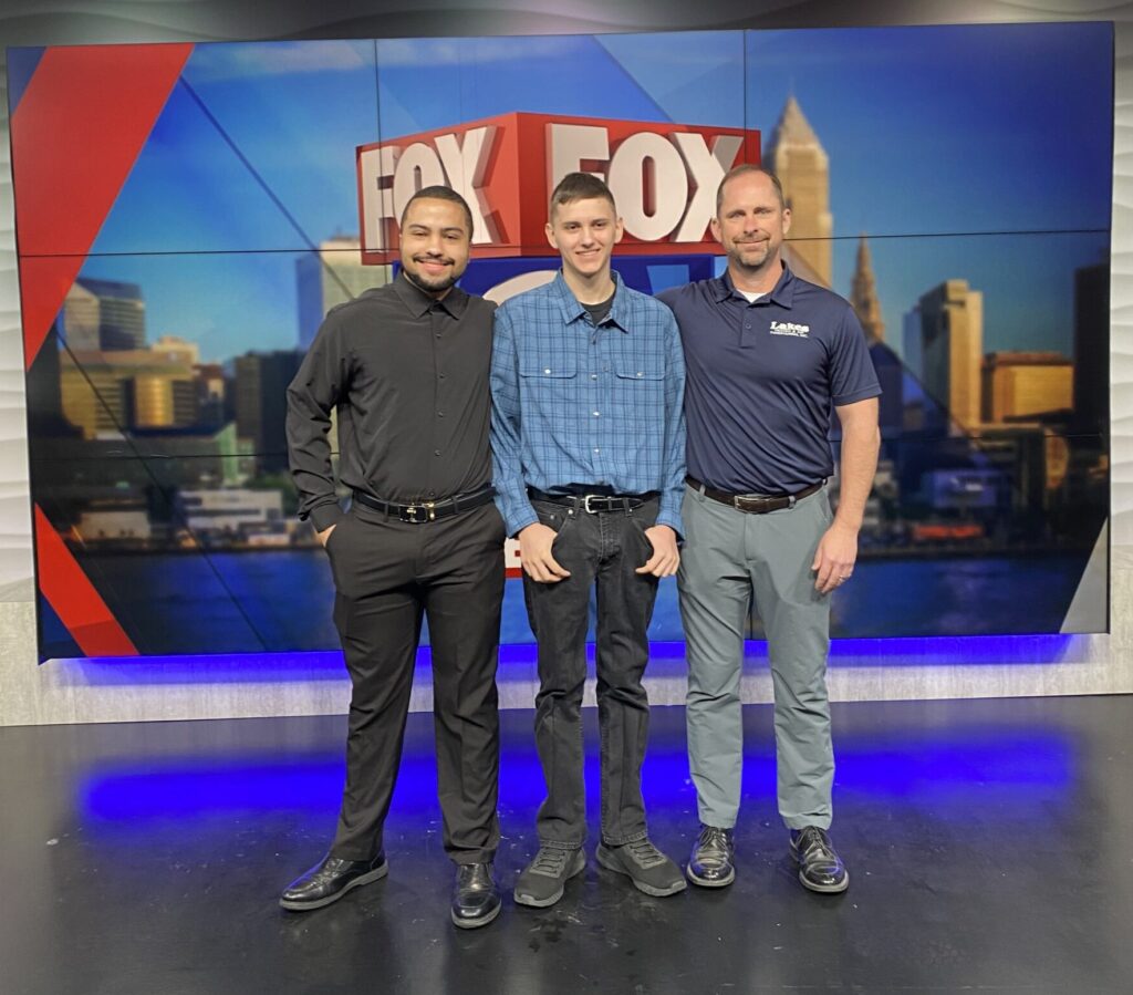 Recipient of the Lakes Heating Trades Scholarship in front of a news backdrop